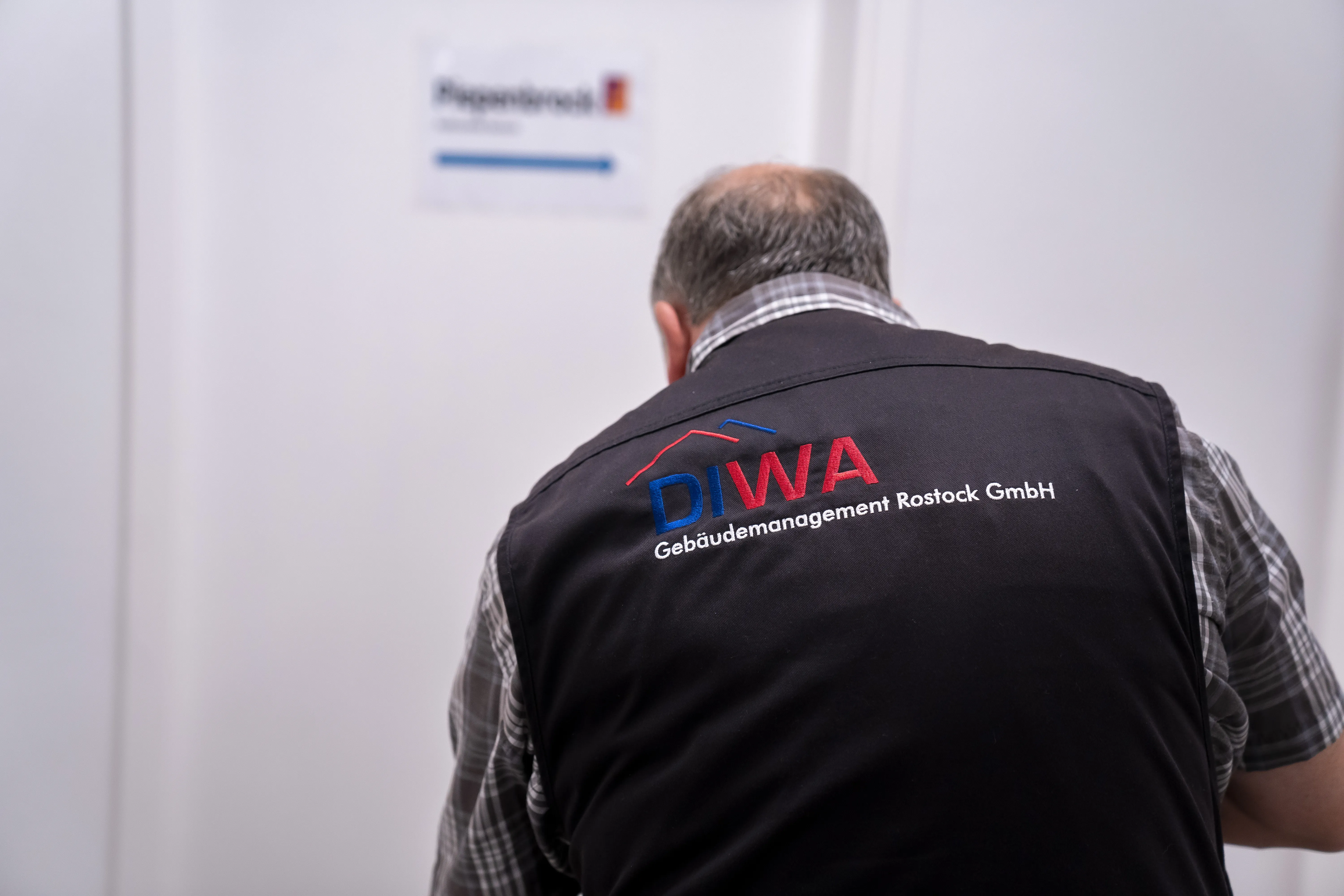 Ein Mitarbeiter der DIWA Gebäudemanagament Rostock GmbH beim Arbeiten mit einer Weste, auf der das Logo der DIWA zu sehen ist